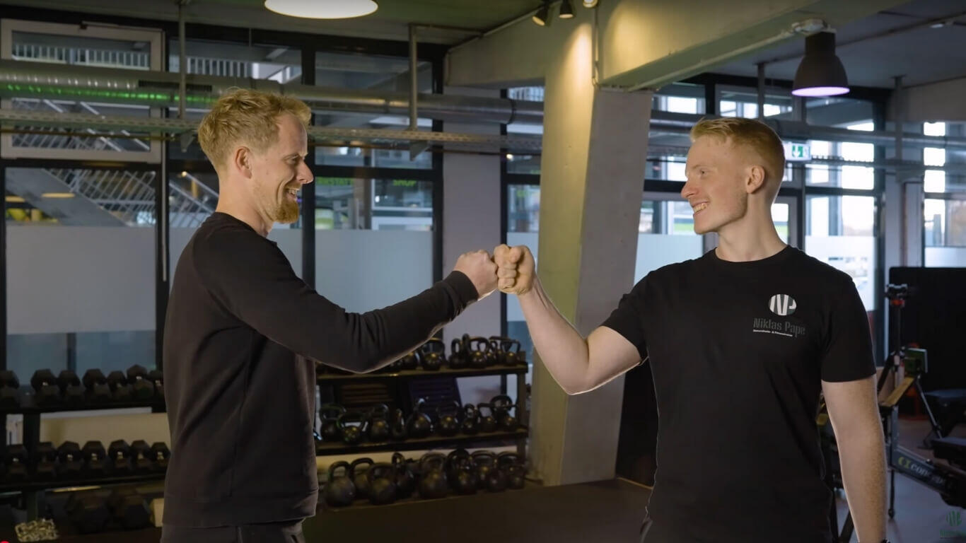 Zwei Männer geben sich im Fitnessstudio einen Fistbump nach erfolgreichem Training