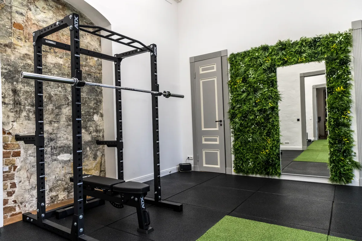 ATX Rack vor historischer Steinmauer mit Pflanzenwand und Spiegel